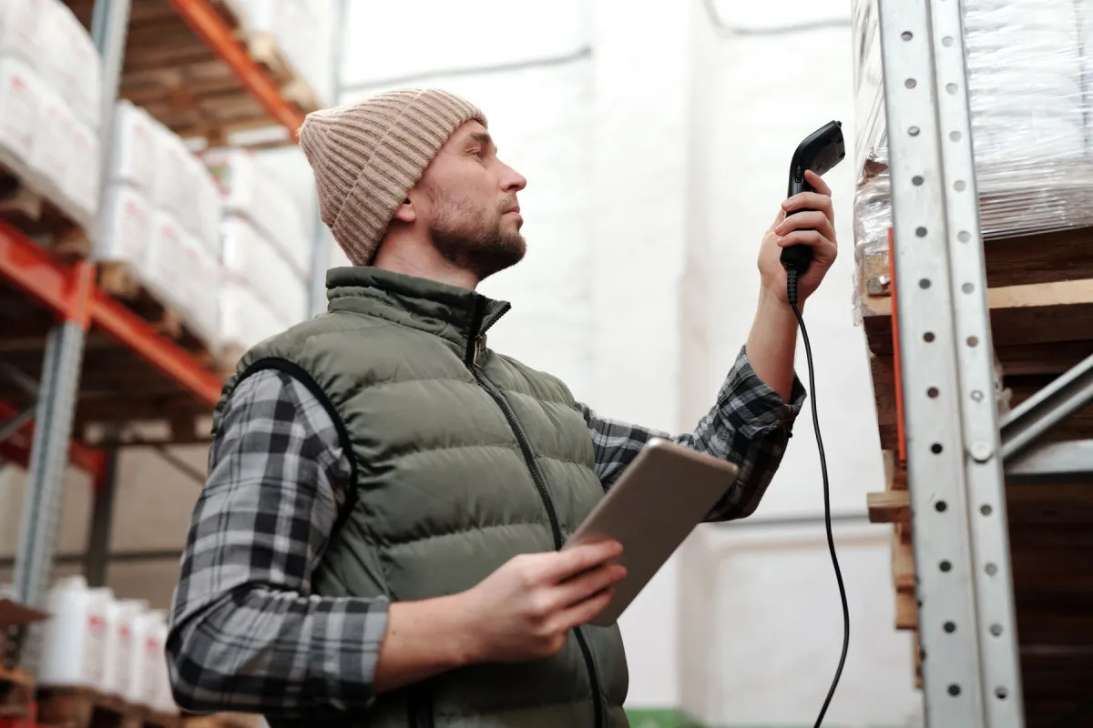 A warehouse worker scanning inventory while holding a tablet