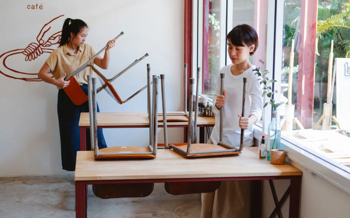 Two cafe workers preparing tables before service